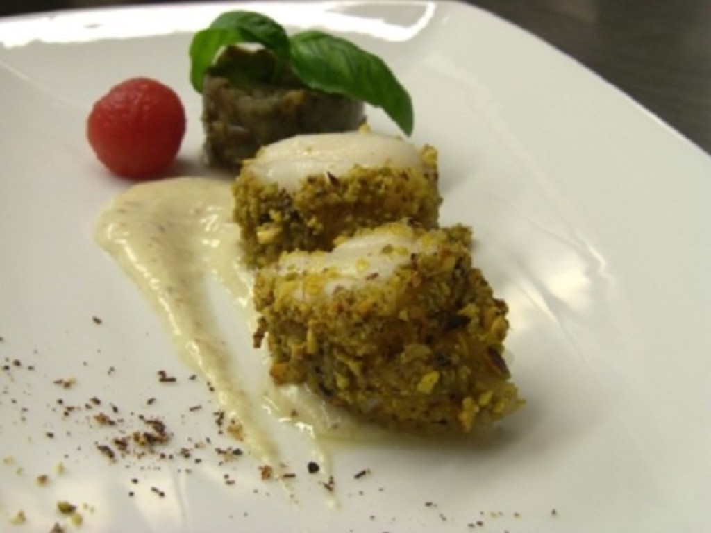 Pescatrice in crosta di pistacchio in crema di pepe e miele  con timballo di carciofi alla menta e acciughe.