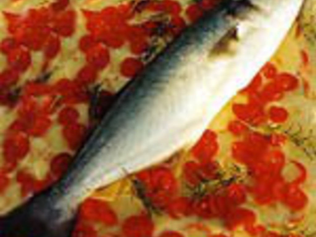 Pesce al forno su un letto di patate e pomodorini