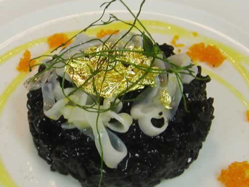 Risotto al nero di seppia con la foglia d'oro, tagliatelle di calamari e contrasto di mango