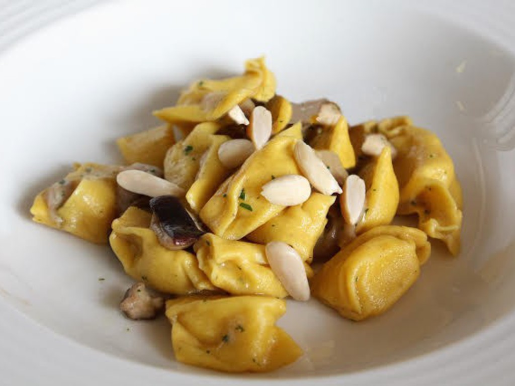Ravioli pizzicati con ripieno di cipolla e parmigiano liquido con funghi e nocciole